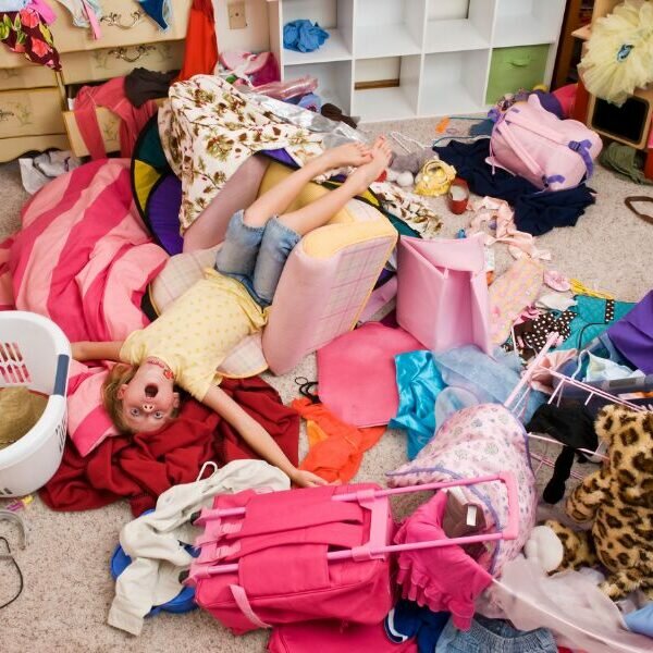 this is a photo of a very cluttered kid's room with a child laying in the middle of it